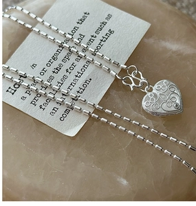 Macro detail of S925 sterling silver heart necklace with hollow pattern and bamboo chain