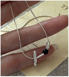 Close-up of S925 silver necklace with minimalist geometric pendant and black bead detail