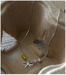 Macro shot of silver bow pendant with translucent green, yellow and purple beads