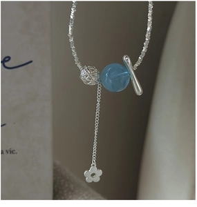 Vue macro du collier en argent S925 avec pierre bleue claire et pendentif fleur ajouré