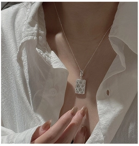 Macro detail of a vintage S925 silver rhombic pendant on a model with white shirt