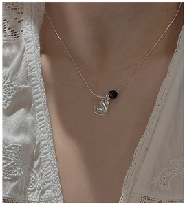 Detail of S925 silver heart necklace with black onyx bead on a model neck