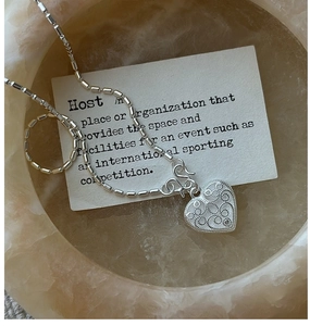 Macro shot of S925 silver heart pendant with filigree details and cylindrical bead chain