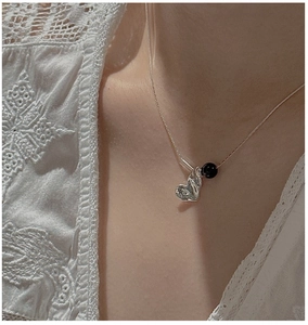 Detail of vintage heart pendant and black onyx bead on a delicate silver chain