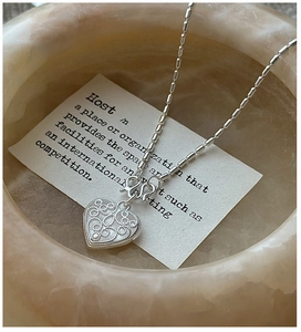 Macro shot of S925 sterling silver heart pendant with intricate filigree texture detail