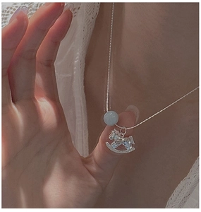 Primo piano della collana cavallo a dondolo in argento S925 con perla blu su modella