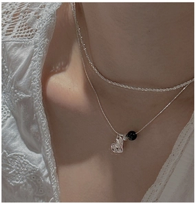 Detail of layered S925 silver necklaces with irregular heart pendant and black onyx bead