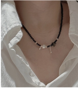 Detail of S925 silver necklace with black agate beads and central metallic pendants