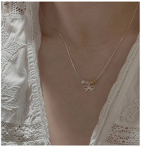 Detail of S925 silver bow necklace with colorful beads on a model wearing white lace