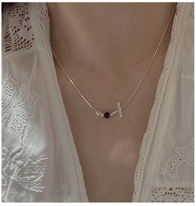 Detailed view of S925 silver T-bar necklace with black bead on a lace outfit