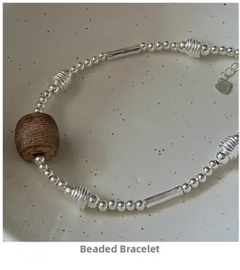 Detail of S925 silver beaded bracelet with brown wooden bead in a ceramic bowl