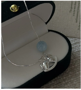 Dettaglio collana d'argento con ciondolo a cavallo e perla blu su scatola di velluto