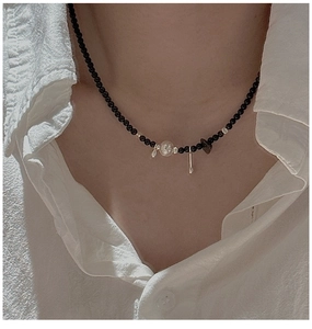 Detail of S925 silver necklace with black beads and vintage metallic charms on model