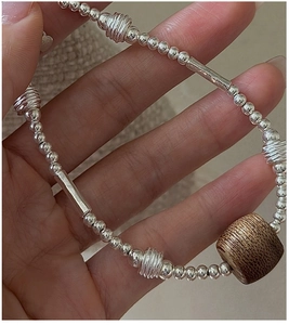 Close-up of S925 silver beaded bracelet with a distinct brown wooden bead and spiral charms