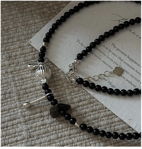 Macro detail of S925 silver heart tag and black onyx beads on a vintage necklace