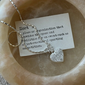 Vintage S925 sterling silver heart necklace with filigree detail on marble tray