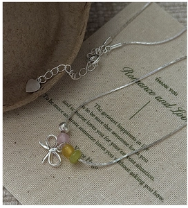 Detail of S925 silver bow necklace with colorful beads and adjustable heart charm chain