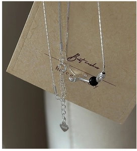 Macro view of S925 sterling silver snake chain with black bead and heart pendant