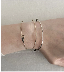 Detailed view of three-piece layered bracelet set with key charm and ruby zircon on wrist