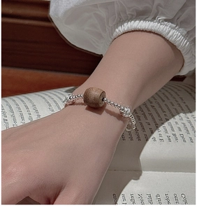 Macro detail of S925 silver beaded bracelet with natural wood bead on a book