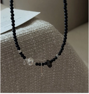 Detailed shot of S925 silver hollow bead and long pin pendant on black onyx necklace