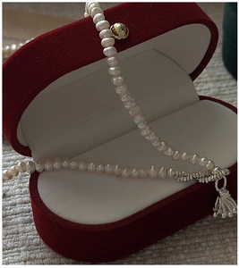 Detail of natural freshwater pearl necklace with silver tassel in a red velvet gift box