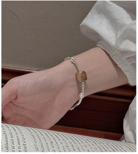 Detail of S925 silver beaded bracelet with dark wood bead on wrist with book