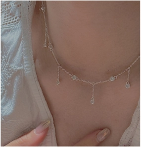Détail du collier argenté S925 avec glands en zircone porté sur le cou avec dentelle