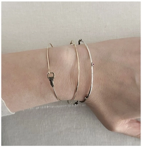 Detail of S925 silver twig bracelet and gold key bangle worn on a model's wrist