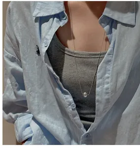Detail of silver long beaded necklace with a circular pendant on a lifestyle model
