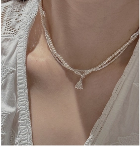 Detail of layered S925 silver pearl necklace featuring a shell pendant and lace accents