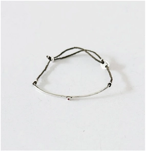 Macro detail of S925 silver curved bar on green cord with a small red zircon gemstone