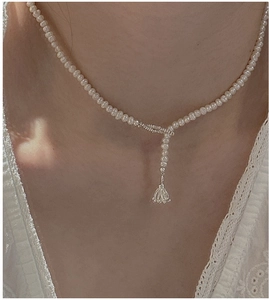 Detail of S925 sterling silver pearl necklace with Y-shaped floral pendant on neck