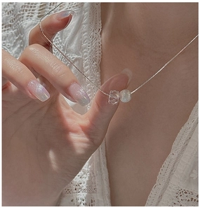 Detail of S925 silver necklace with faceted crystal and green bead on white lace
