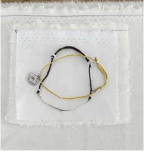 Close-up of handmade yellow and brown braided rope bracelets with silver engraved charms