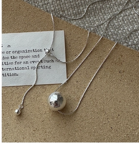 Close-up of S925 silver beaded necklace with adjustable sliding clasp on textured paper