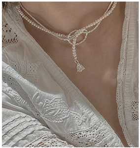 Close-up of S925 silver pearl necklace featuring a knotted design and bell pendant