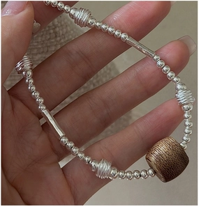 Macro shot of S925 sterling silver beads with natural dark wood bead on a textured wrist