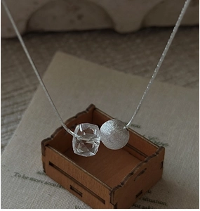 Detail of silver brushed bead and clear crystal pendant on a delicate chain necklace