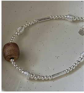 Close-up of S925 silver beaded bracelet featuring vintage wood barrel beads and heart charm