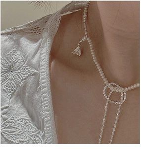 Detail of S925 silver vintage pearl necklace with bell pendant on model with lace top