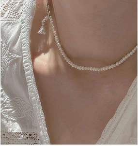 Macro shot of S925 silver pearl necklace with detailed bell pendant on a model