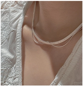Detail of layered S925 silver necklace with textured snake chain and thin cable chain