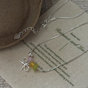 S925 sterling silver necklace with bow pendant and colorful beads on vintage background