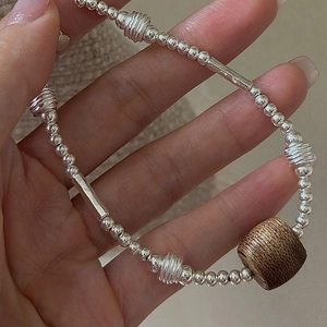 Minimalist S925 silver beaded bracelet with dark wood barrel bead held in hand