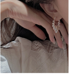 Detailed close-up of a high-polish silver croissant hoop earring worn by a model