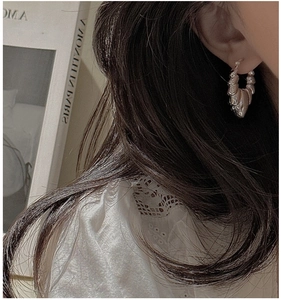 Macro view of silver chunky croissant hoop earrings with textured segmented design