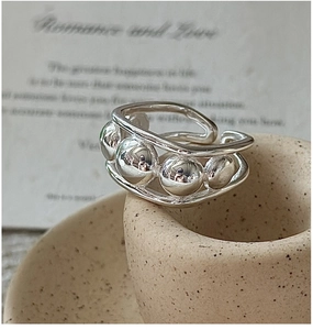 Macro detail of S925 sterling silver beaded ring on artistic beige ceramic base