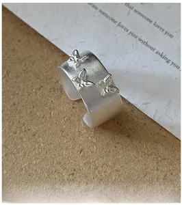 Détail de la bague large ouverte en argent mat avec trois papillons en relief sculptés