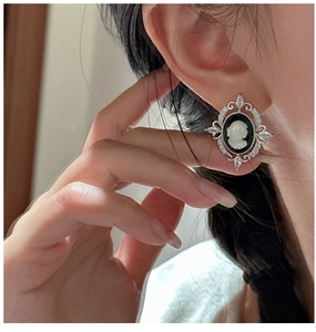 Detail of vintage S925 silver cameo earrings with embossed girl profile and zircon accents